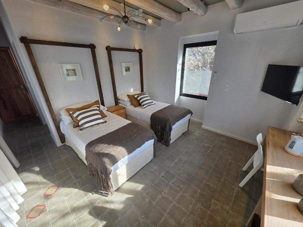 Una habitación con dos camas, techo de madera, ventana y televisor.