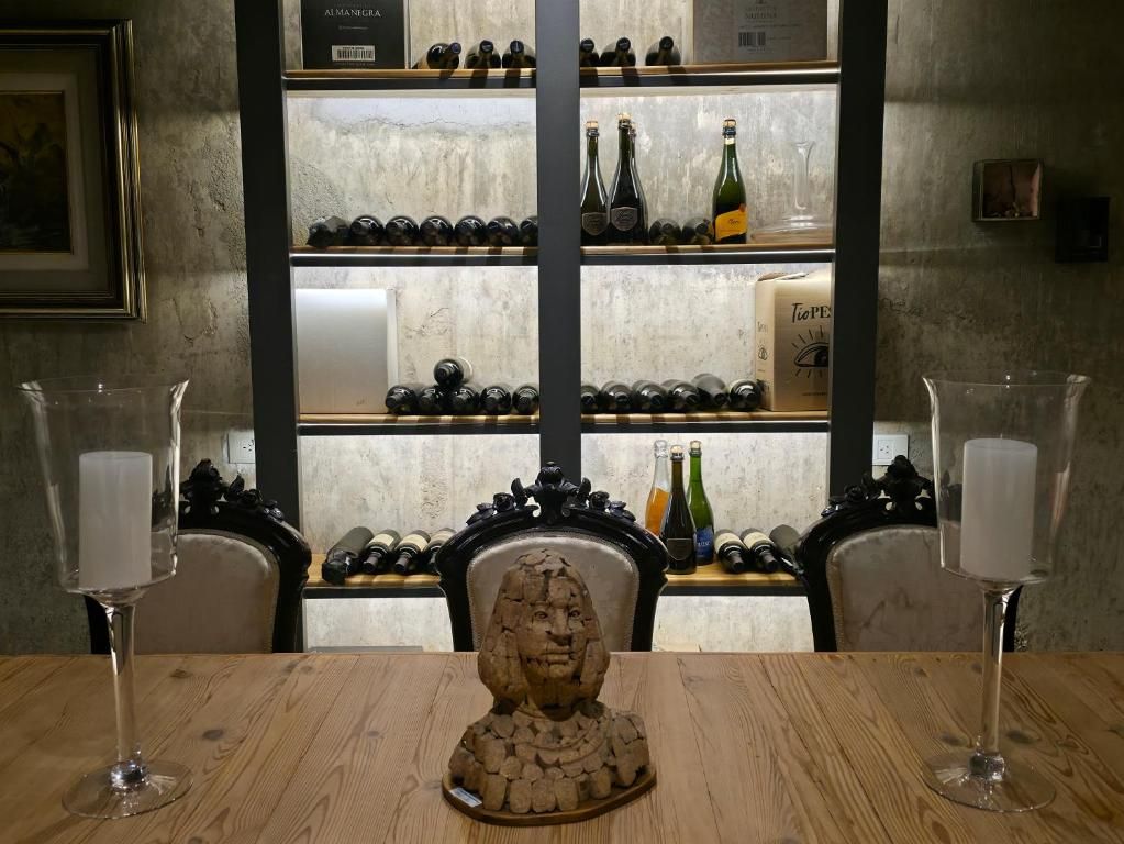 A table with a sculpture centerpiece, wine glasses, and a wine rack in the background.