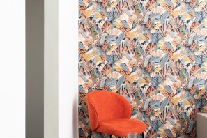 A room with a patterned wallpaper, a single orange chair, and a small table. - La Casa di Renato | 2BR in the heart of Sorrento (Sorrento)