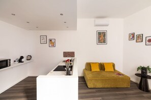 A modern living room with a sofa, a coffee table, a kitchen area with a microwave, and a staircase. - La Casa di Renato | 2BR in the heart of Sorrento (Sorrento)