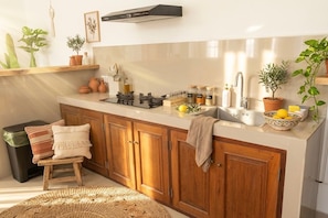 A kitchen with wooden cabinets, a gas stove, a sink, and various kitchen items. - Bohemian Luxury 3 BR  In the Center of Canggu with Pool (Canggu, Kabupaten Badung)