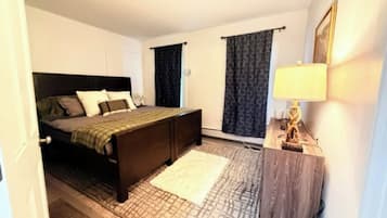 A bedroom with a bed, bedside table, lamp, and curtains.
