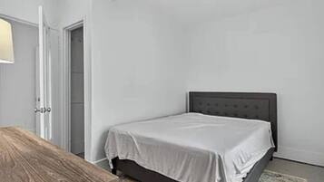 Une chambre à coucher avec un lit, une table de chevet en bois et une porte.