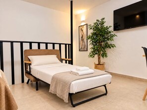 A single bed with a headboard, a bedside table, a wall-mounted TV, a potted plant, and a framed artwork. - Nova Plebiscito 3 One Minute From Plebiscito (Naples)