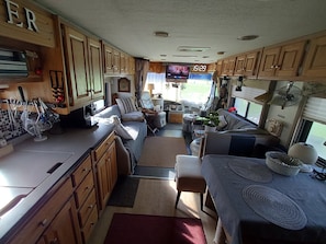 A compact RV interior with a kitchenette, seating area, and a television. - Tiny Home 'Lotte in Seidenroth' with private garden and Wi-Fi (Steinau an der Straße)