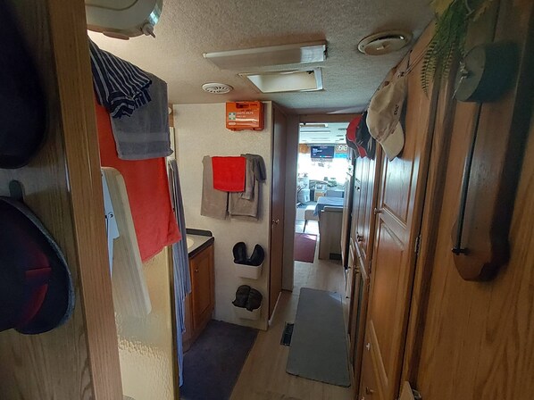 A narrow hallway with a kitchenette area, a small seating area, and a door leading to an outdoor space.