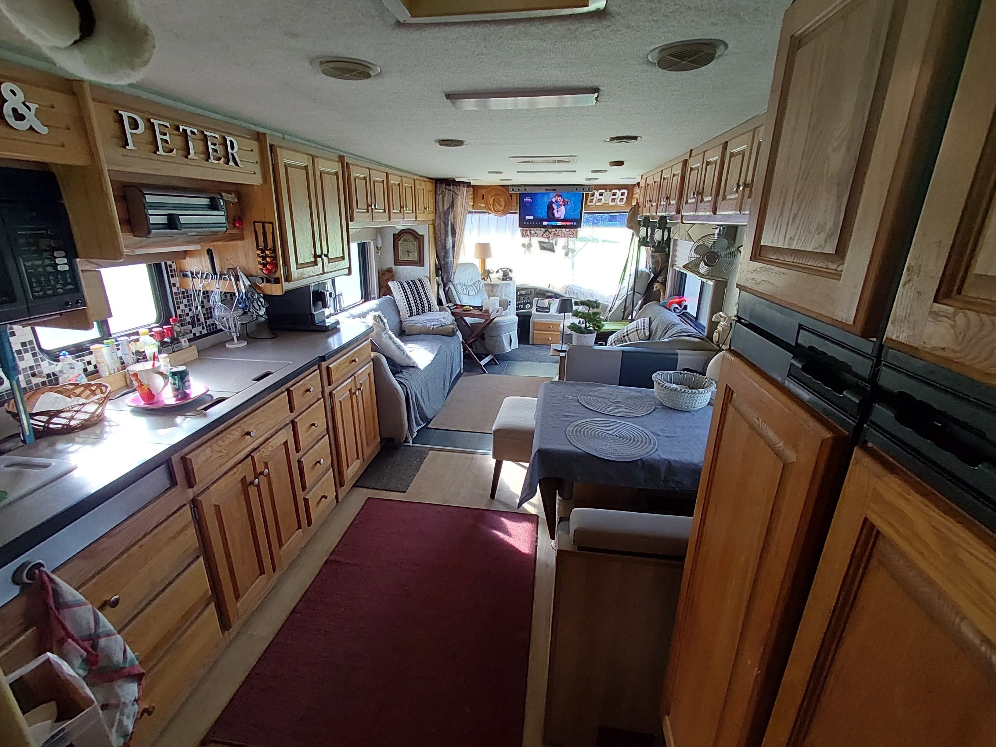 Interior compacto de una casa rodante con kitchenette, comedor y sala de estar.