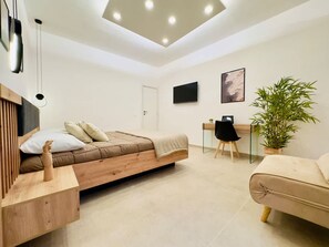 Ein modernes Schlafzimmer mit Bett, Nachttisch, Schreibtisch, Stuhl und einer Topfpflanze.