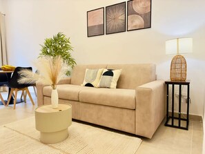 A living room with a beige sofa, a round side table, a lamp, and a plant. - Nova Plebiscito 1 Suite in Naples Center (Naples)