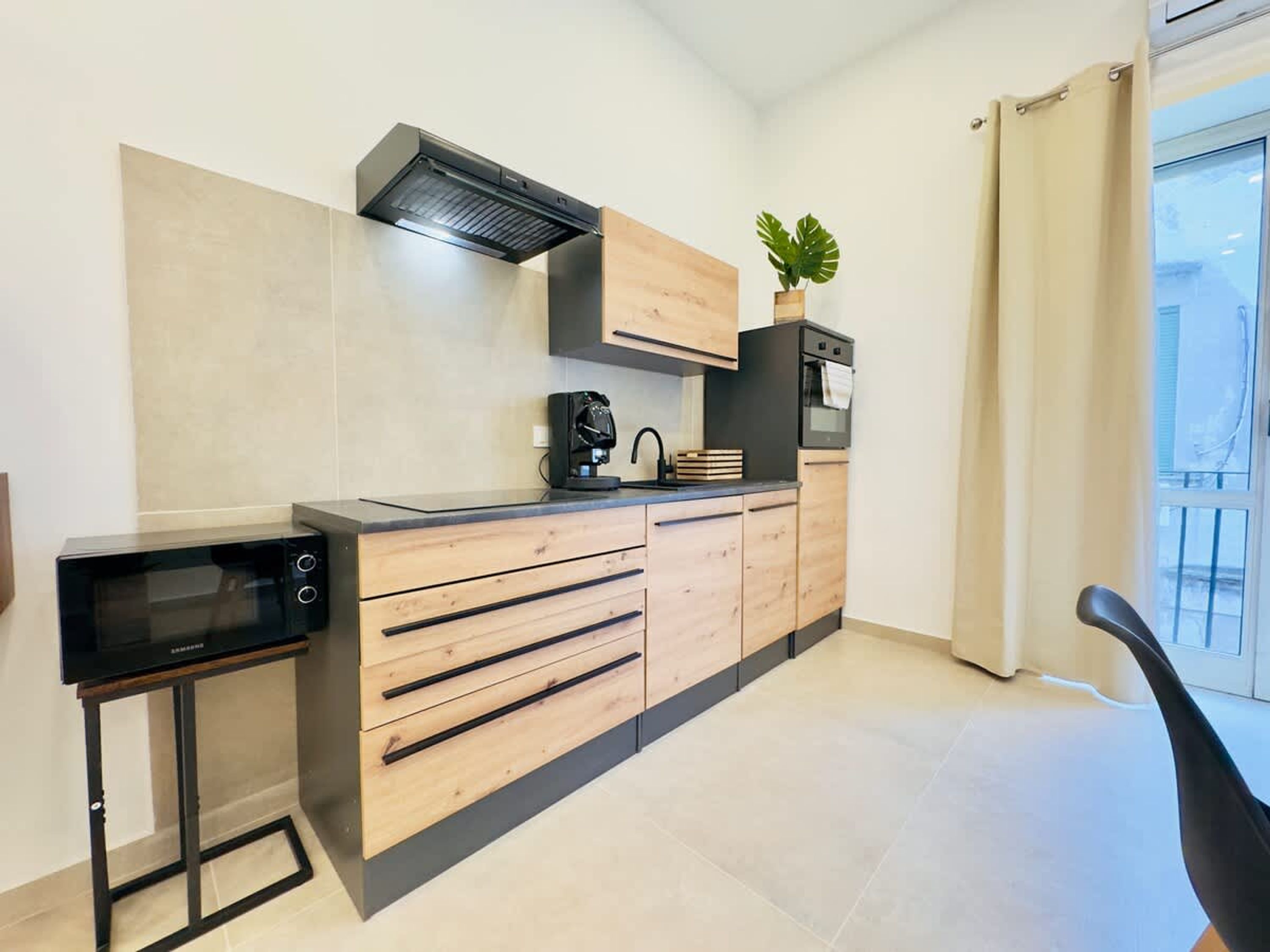 A compact kitchen with a built-in microwave, a coffee machine, and a small oven.