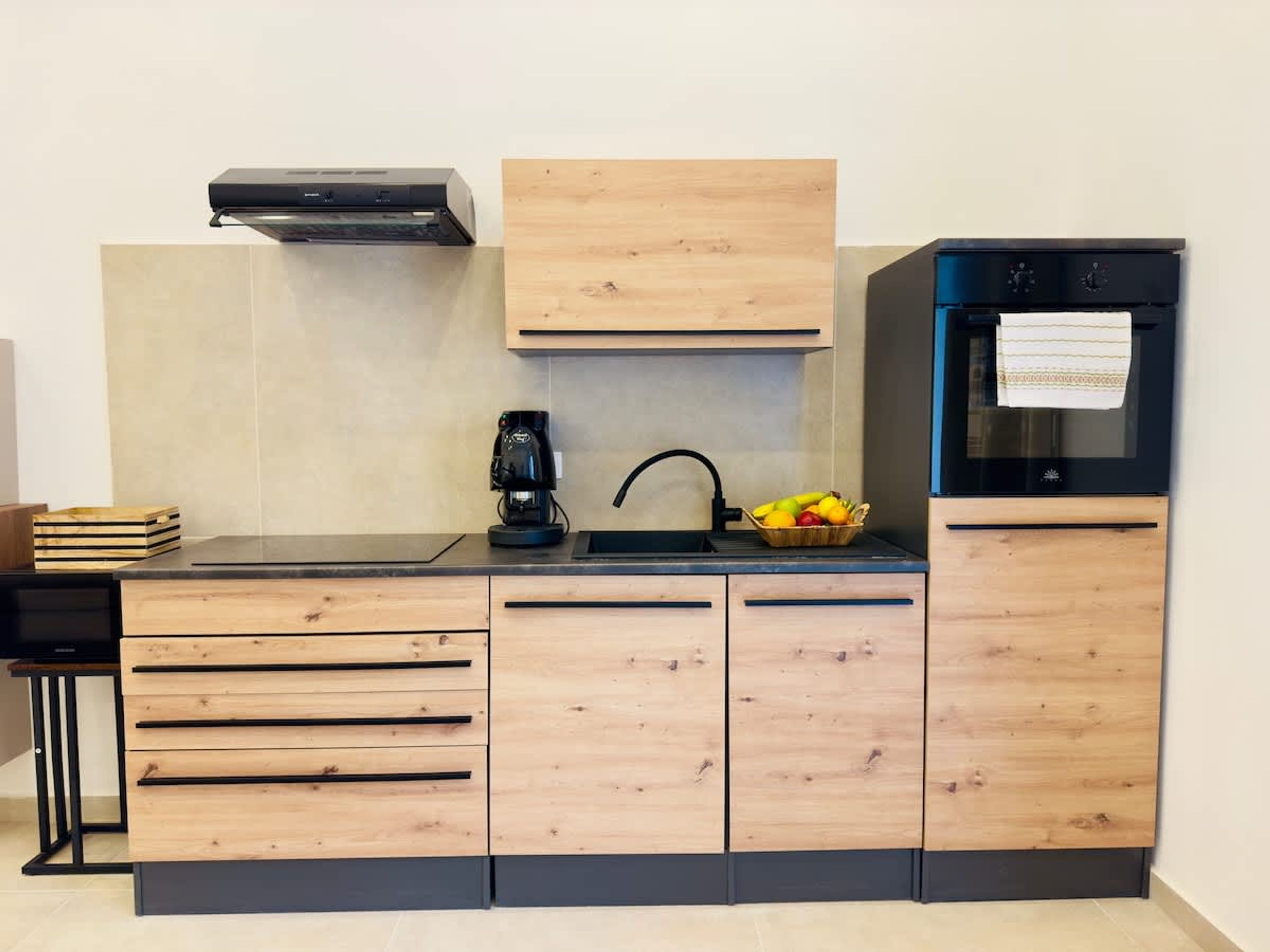 A modern kitchen with wooden cabinetry, a coffee maker, a sink, and a refrigerator.