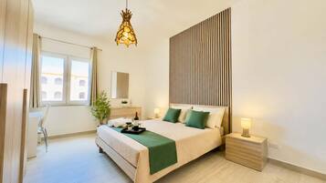 A modern bedroom with a bed, bedside tables, a desk, and a hanging light fixture.