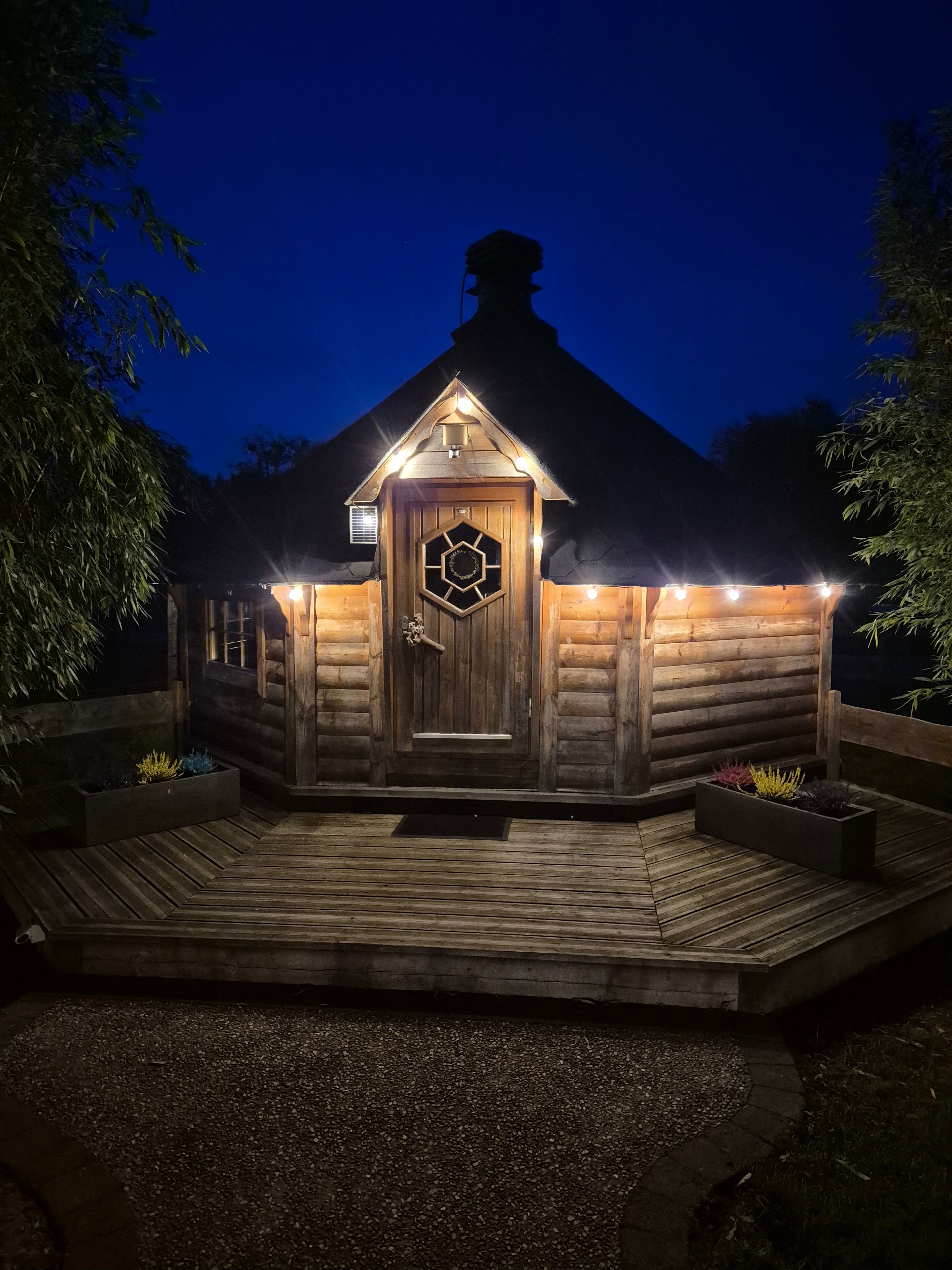 A wooden cabin with a hexagonal door and a porch.