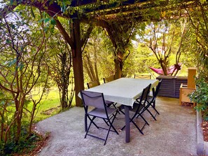 Eine Gartenpatio mit Tisch und Stühlen, umgeben von Bäumen und Grün.