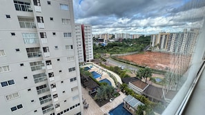 A high-rise building with multiple balconies, a swimming pool, and a landscaped area with palm trees. - CRCN - Evian Thermas Residence (Caldas Novas)