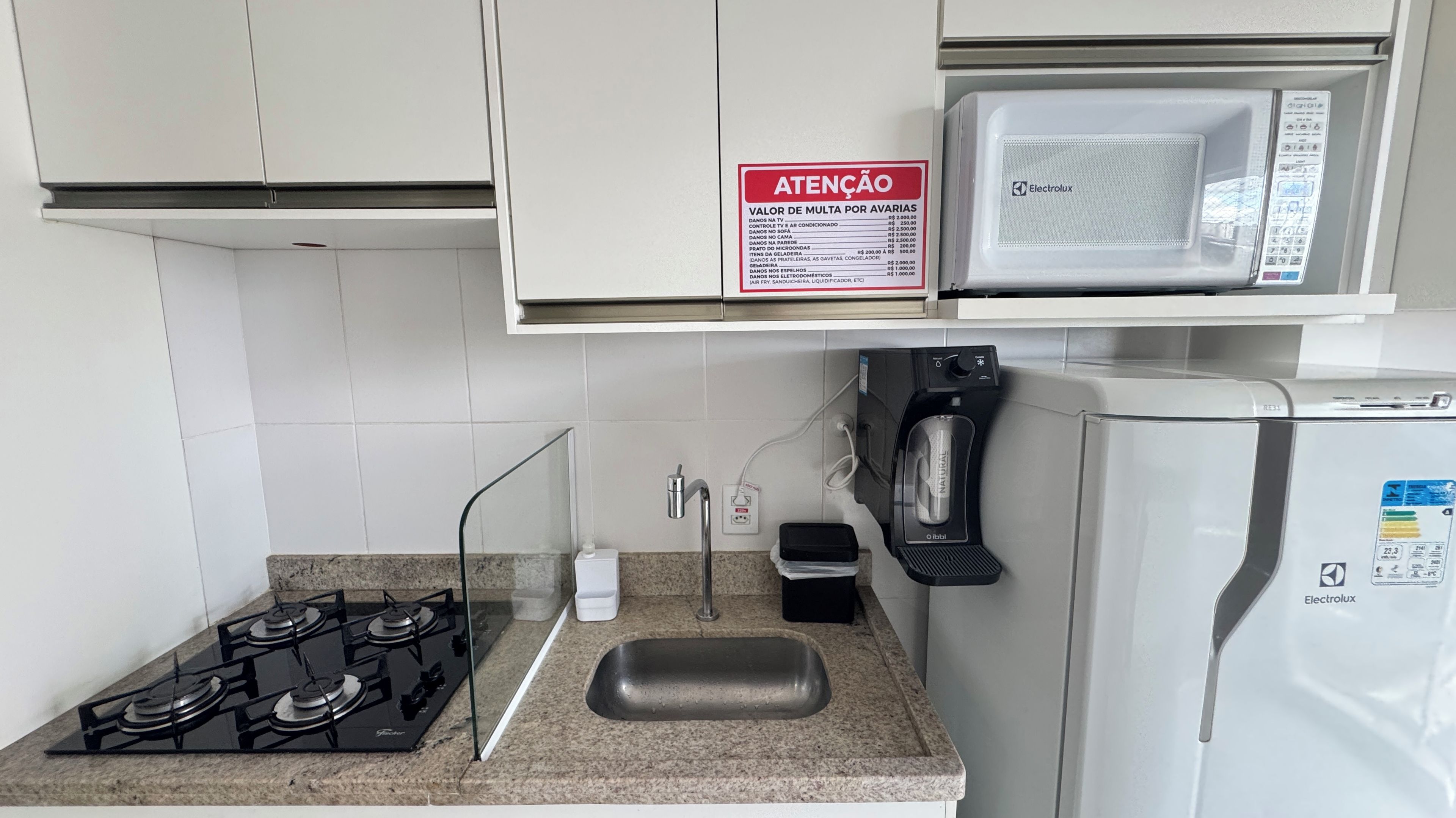 A kitchen with a gas stove, a microwave, and a refrigerator.