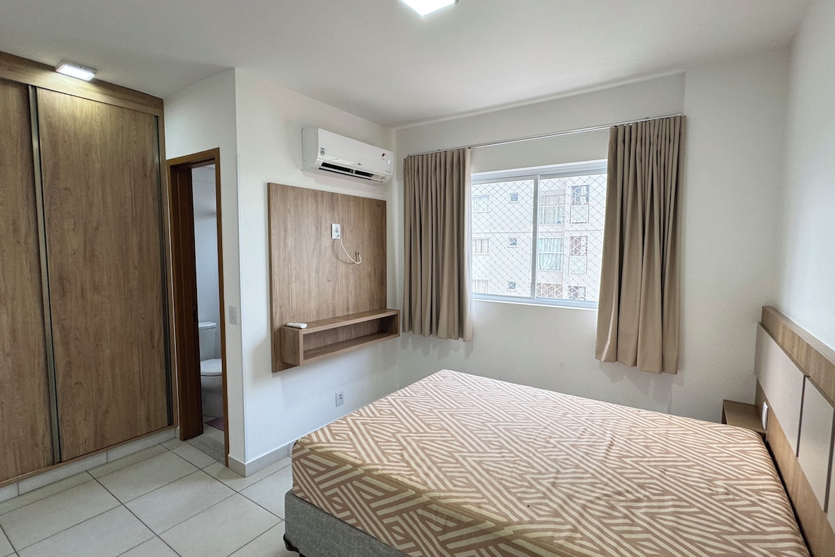 A bedroom with a bed, wardrobe, and a window with curtains.