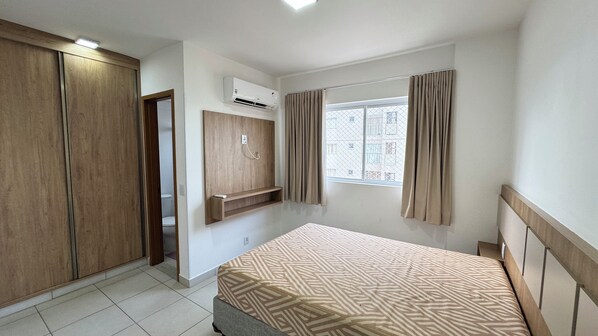 A bedroom with a bed, wardrobe, and a window with curtains.