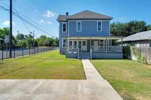 A two-story house with a front porch, a fenced yard, and a speed limit sign. - NEW! Fall in a Victorian | Grand Porches Near DT (San Antonio)