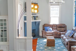 A living room with a fireplace, leather sofas, and a patterned rug. - NEW! Fall in a Victorian | Grand Porches Near DT (San Antonio)