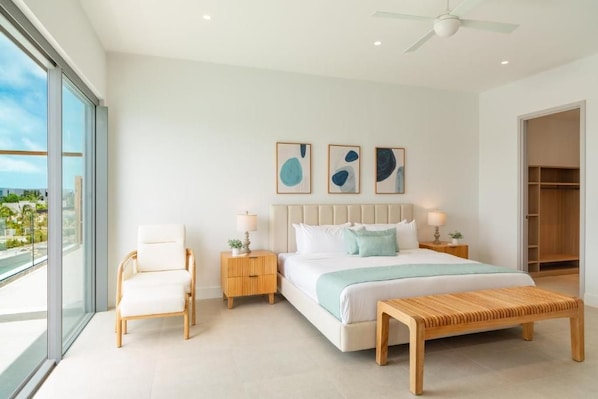 Une chambre à coucher moderne avec un grand lit, des tables de chevet, une chaise et des œuvres d’art accrochées au mur.