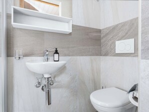 A bathroom with a white sink, a toilet, and a shelf above the sink. - Bright Room near Elm, Kitchenette & Private Bath (Glarus Süd)