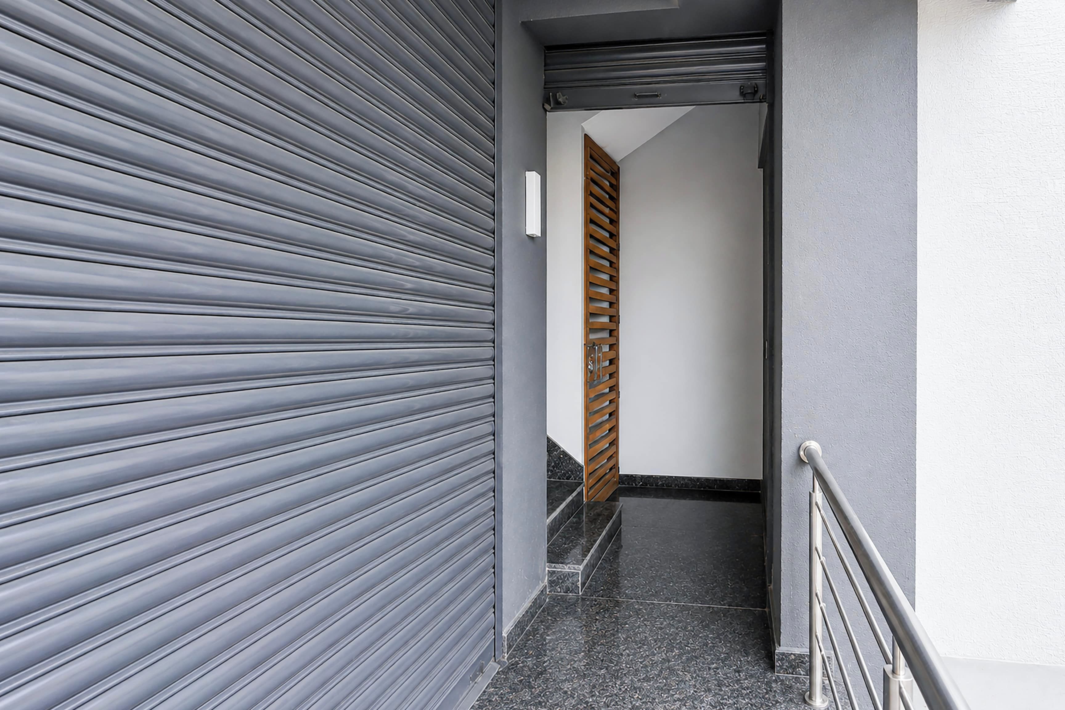 A hallway with a closed sliding door, a wooden door, and a metal handrail.