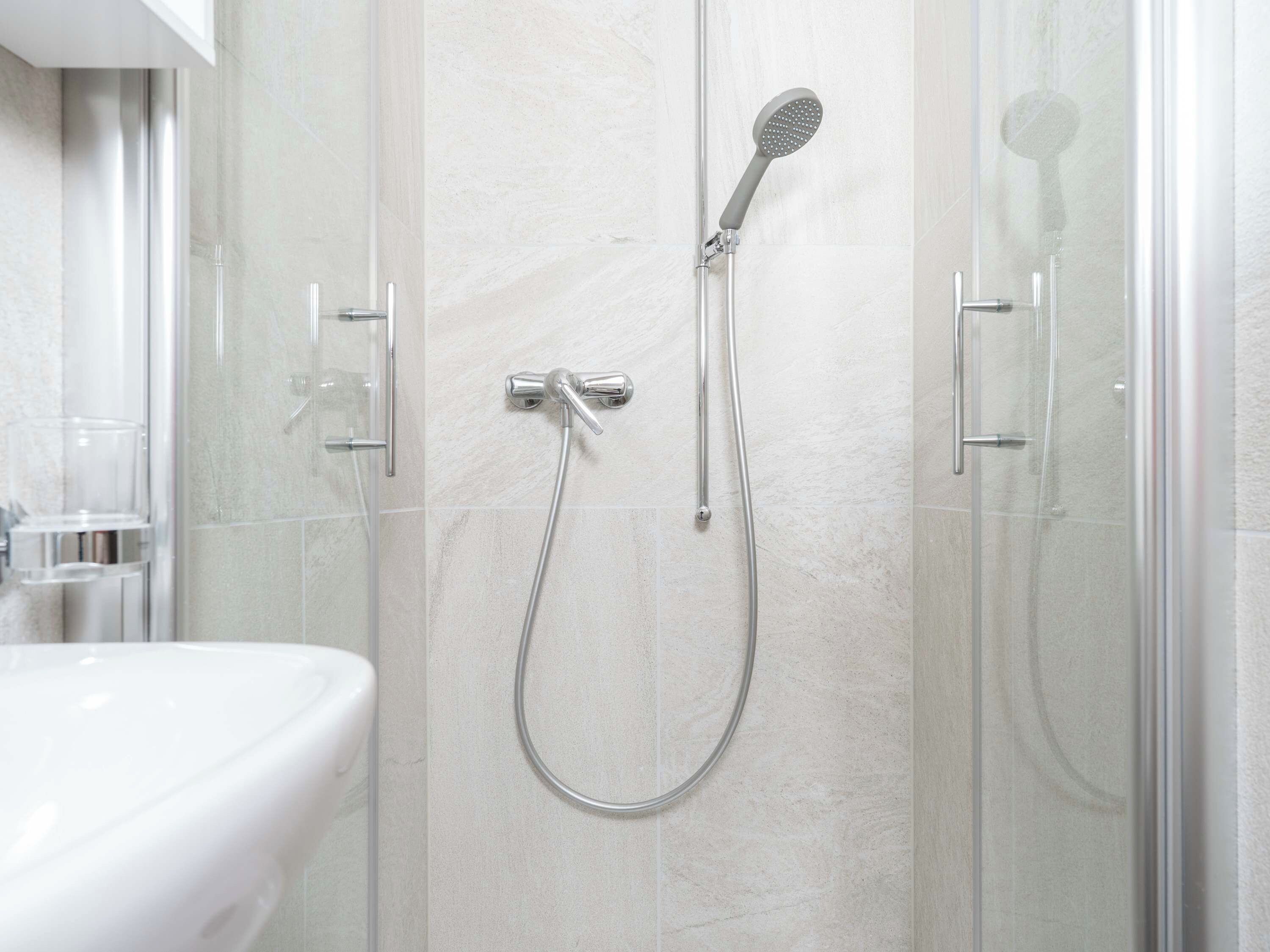 A modern bathroom with a glass-enclosed shower, a white sink, and a glass shower door.