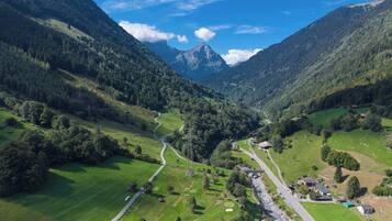 Une vallée traversée par une route sinueuse, un petit village et une montagne en arrière-plan.