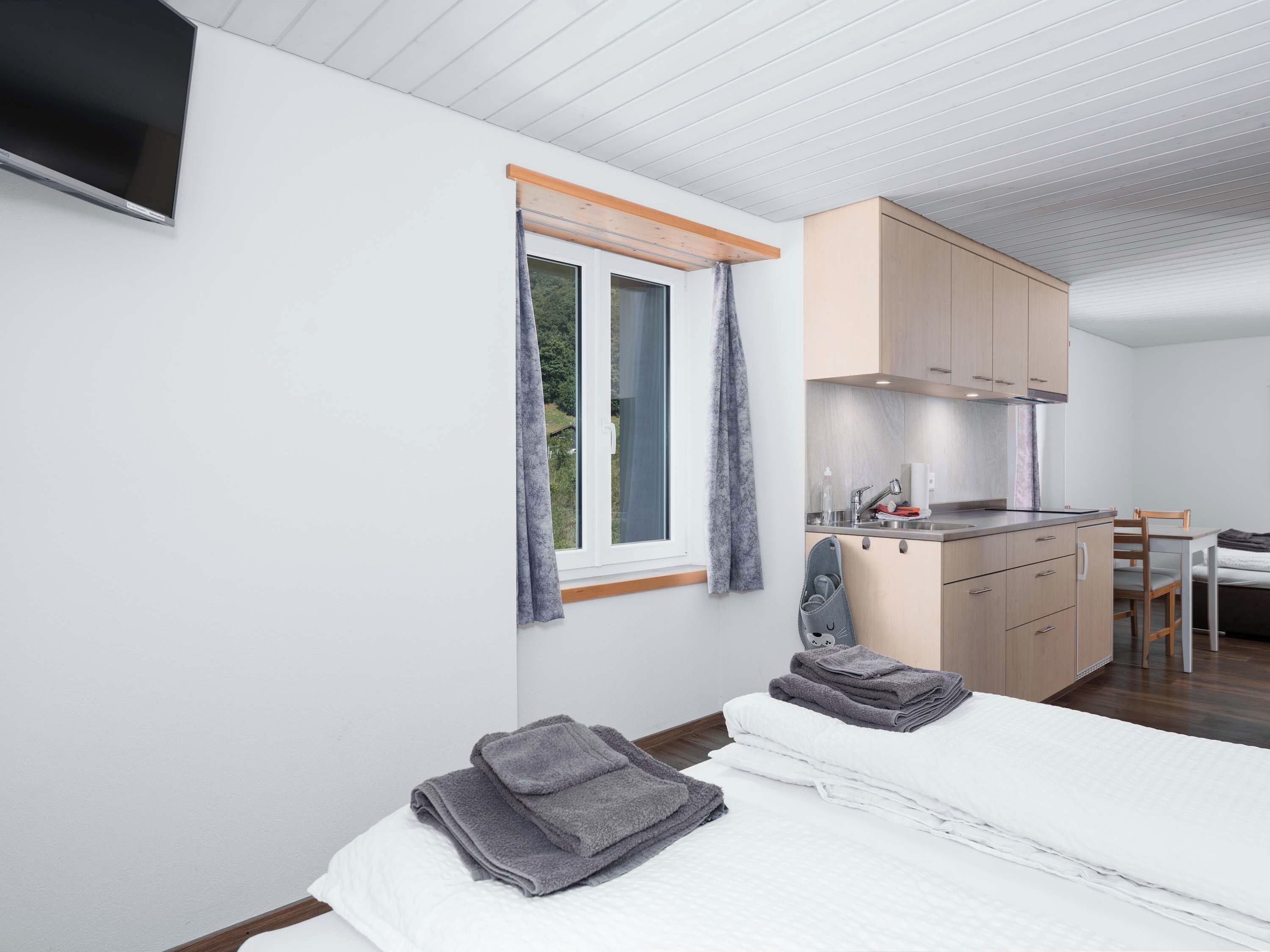 Une chambre à coucher avec un lit, une table de chevet, un petit bureau et une fenêtre avec des rideaux.