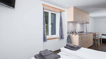 Une chambre à coucher avec un lit, une table de chevet, un petit bureau et une fenêtre avec des rideaux.