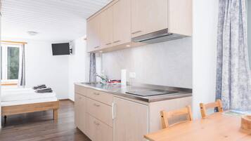 Una cocina moderna con armarios de madera, una estufa empotrada y una zona de comedor con una mesa y sillas de madera.