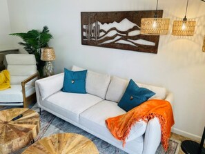 A modern living room with a white sofa, blue cushions, a wooden coffee table, and a decorative wall piece. - Scottsdale Desert Delight with Unbeatable Location (Scottsdale)