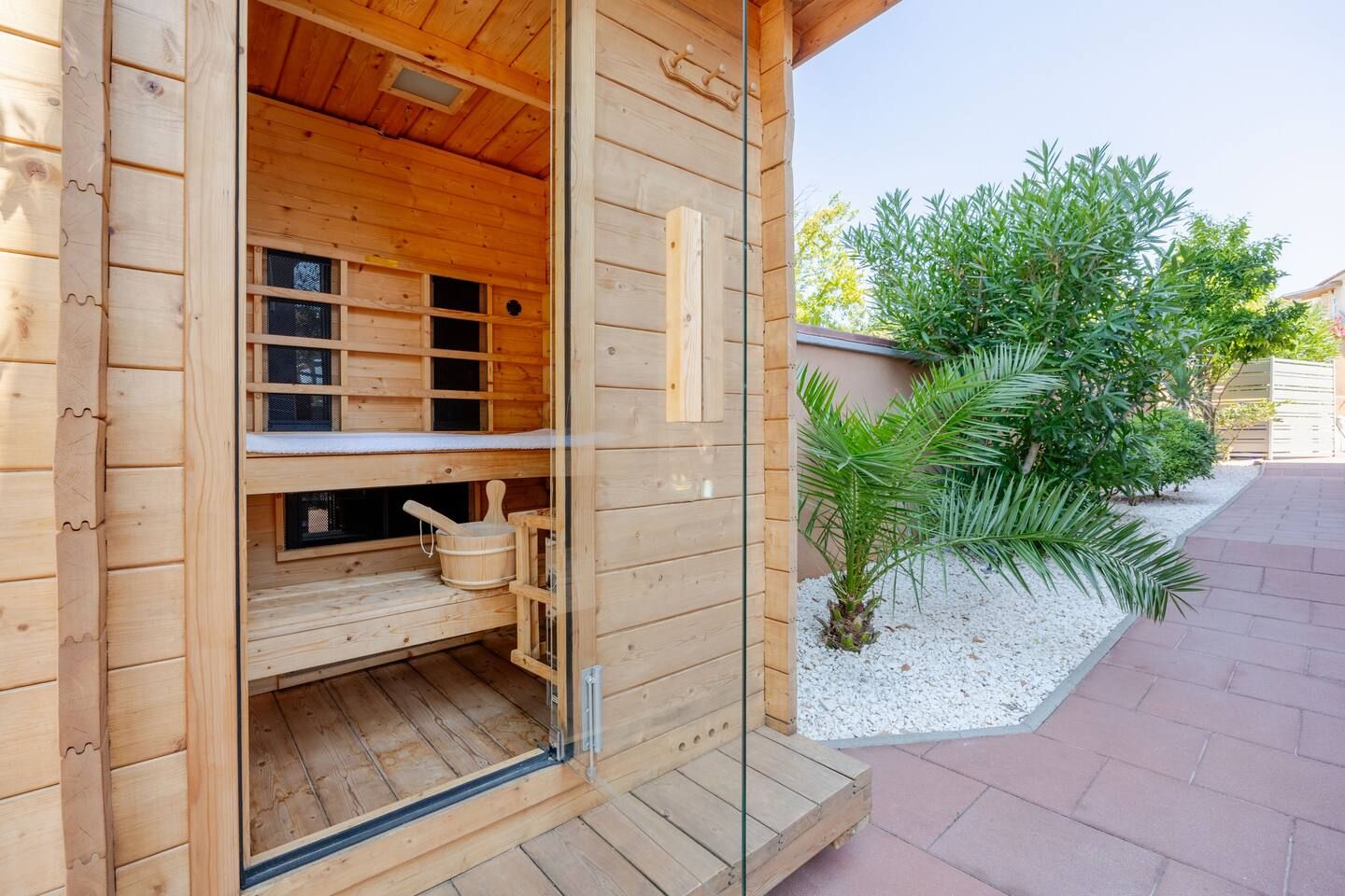 A wooden sauna with a bench, a bucket, and a shelf.