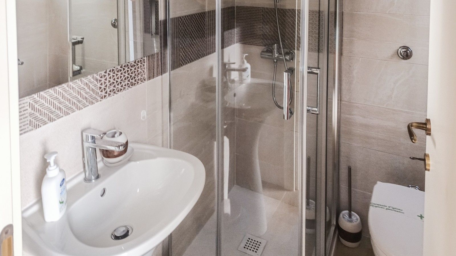 A modern bathroom with a glass shower enclosure, a white sink, and a toilet.