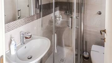 A modern bathroom with a glass shower enclosure, a white sink, and a toilet.