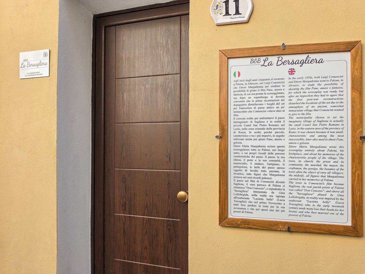 Une porte avec une enseigne au-dessus et un panneau d’information encadré sur le côté droit.