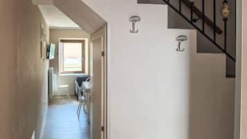 Ein Flur mit Treppe, einem Sessel und einem Tisch.