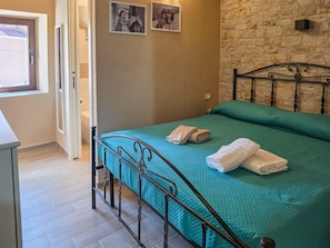 A bedroom with a bed, a stone wall, and a door.