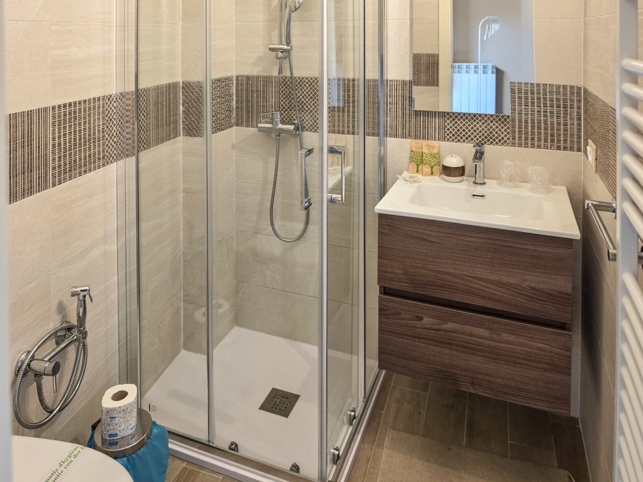 A modern bathroom with a glass-enclosed shower, a wooden vanity, and a mirror above the sink.