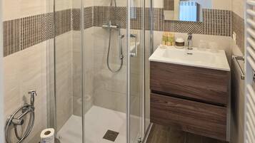 A modern bathroom with a glass-enclosed shower, a wooden vanity, and a mirror above the sink.