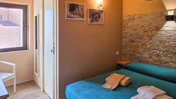 Una camera da letto con un letto, una porta, una finestra e un muro in pietra.