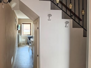 A hallway with a staircase, a chair, and a table in the background. - La Bersagliera - Room 4 (Palena)