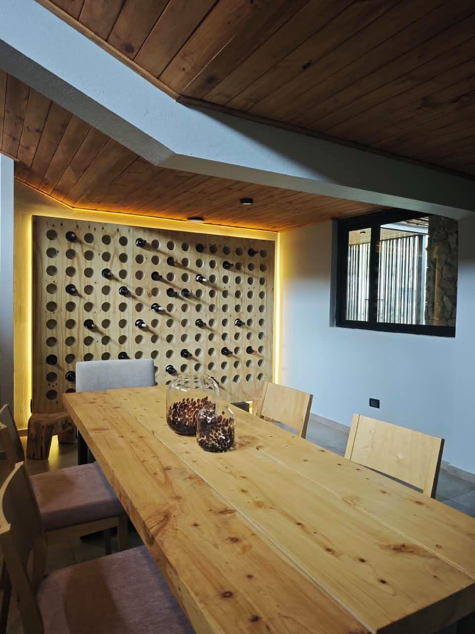 Una mesa de comedor de madera con una estantería para vinos montada en la pared.