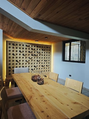 A wooden dining table with a wall-mounted wine rack behind it.