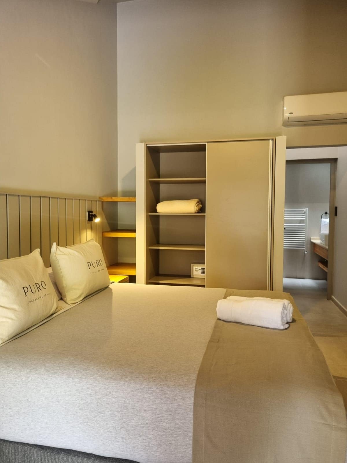 Una habitación de hotel con cama, armario y mesita de noche.
