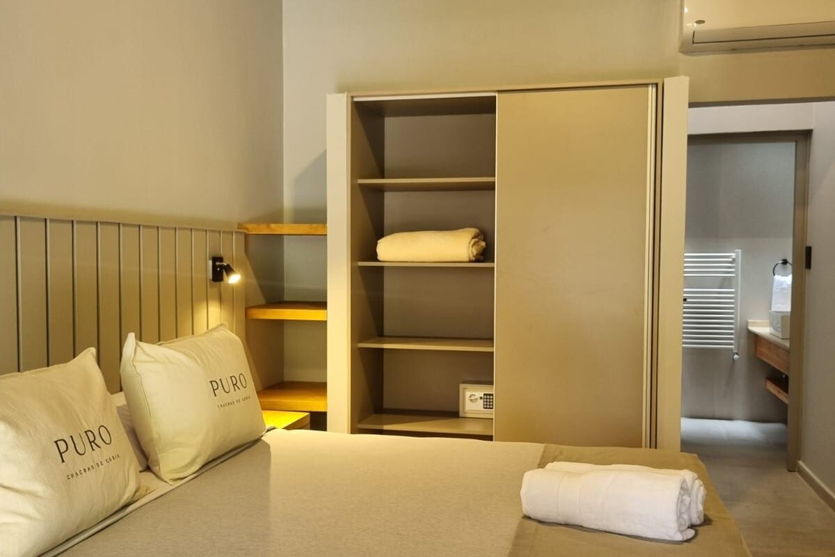 Una habitación de hotel con cama, armario y mesita de noche.