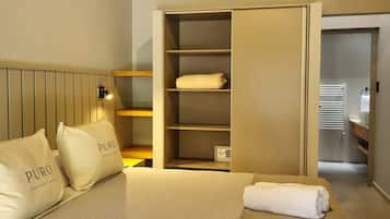 Una habitación de hotel con cama, armario y mesita de noche.