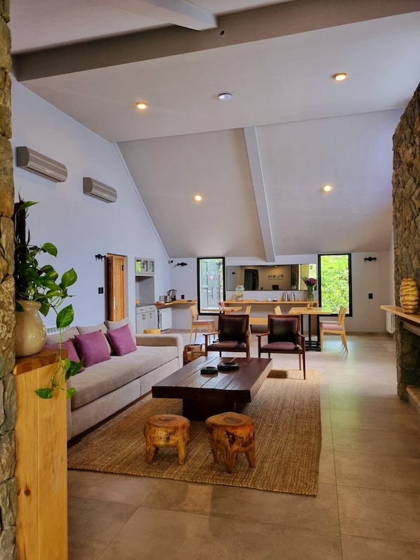 A spacious living area with a high ceiling, a dining area, and a kitchen.
