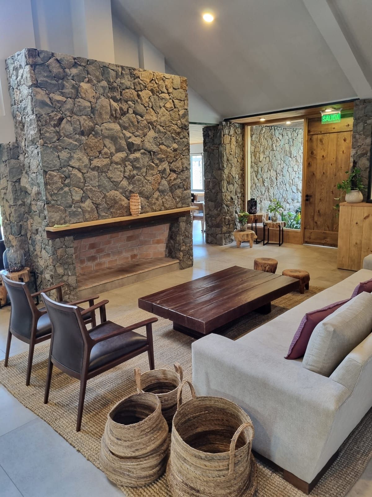 A lobby with a stone wall, a fireplace, seating area, and a sign indicating the exit.